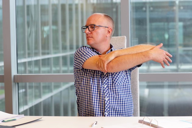 man stretching arm in his office