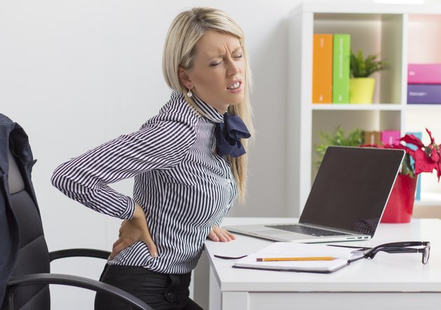 Young woman having back pain at work