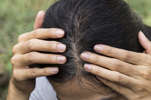 Young woman shows her gray hair roots