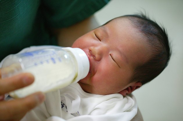 a newborn baby sucking a nursing bottle