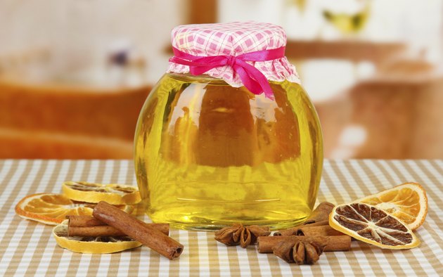 Jar of honey and dried lemon slices on bright background
