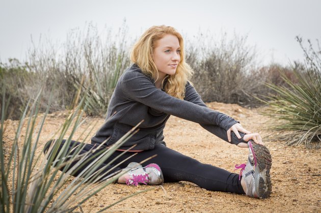 Young female runner stretching to touch toes