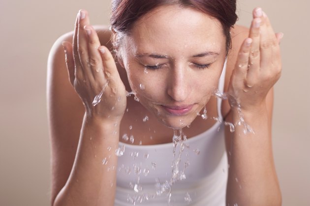 female washing her face with water