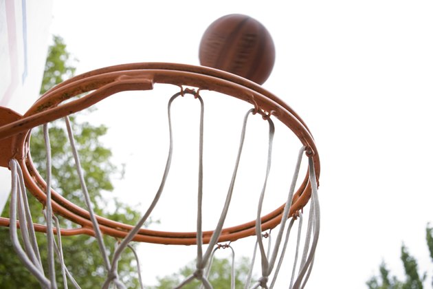 Basketball falling toward hoop on tree-shaded court