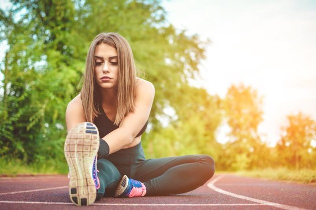 Fit girl practicing stretching exercise at stadium