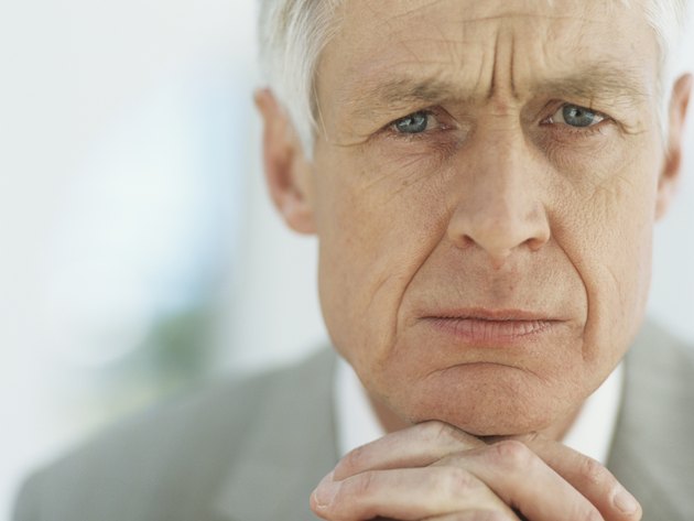 Senior businessman with hands clasped on chin,portrait,close-up