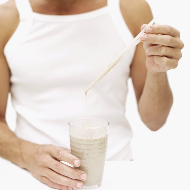 Young man holding a straw over a glass of milkshake