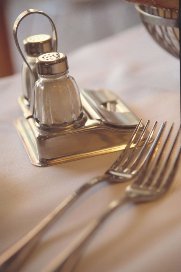 Salt and pepper shakers on table with forks