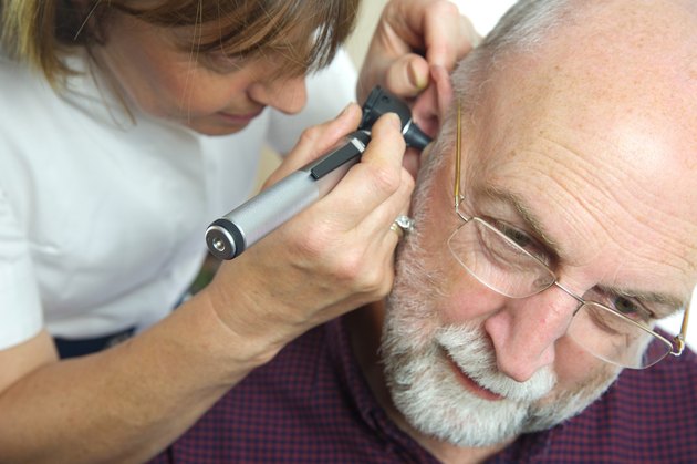 Nurse inspects patient's ear with an auroscope