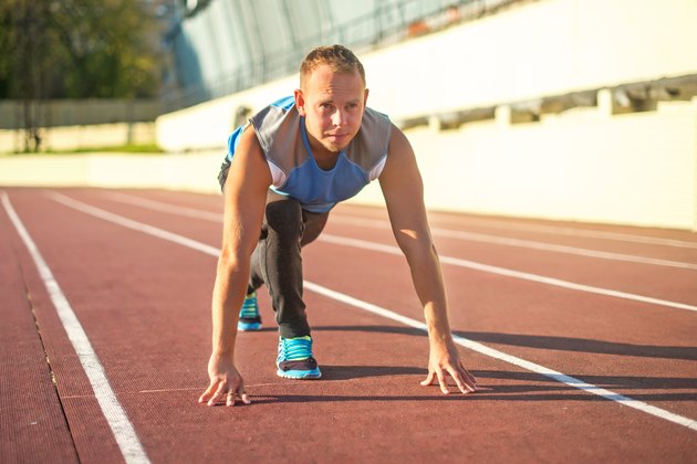 Athletic man standing in posture ready to run on treadmill.