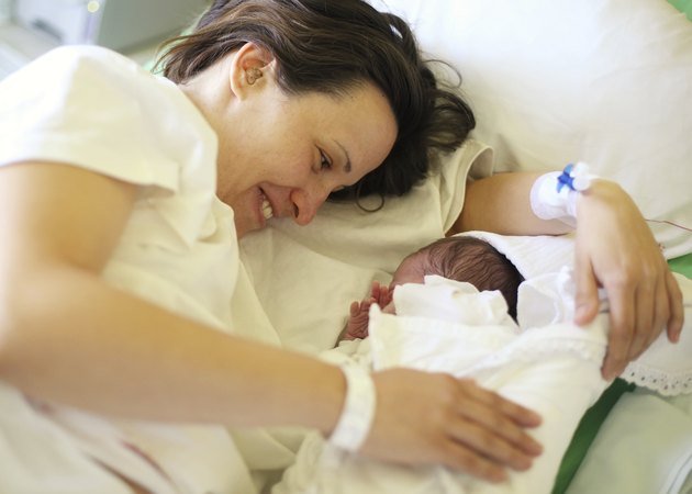 Happy mother with her newborn baby on bed