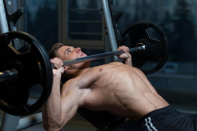 Young Man In Gym Exercising Chest On The Bench Press