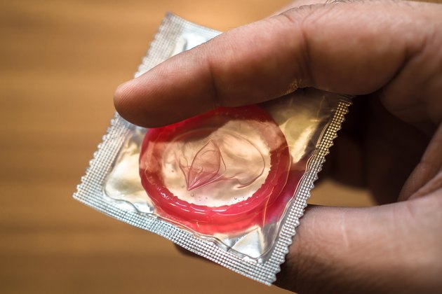 sealed condom in hand on wooden background