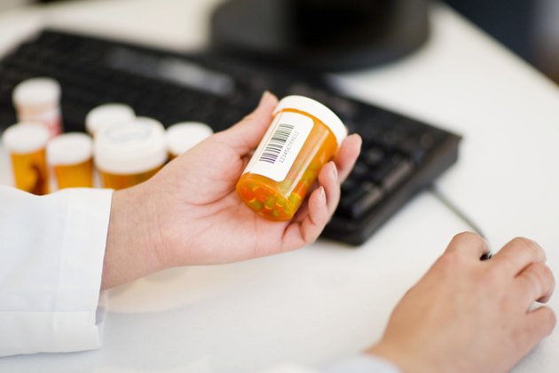 Pharmacist with pill bottles at computer