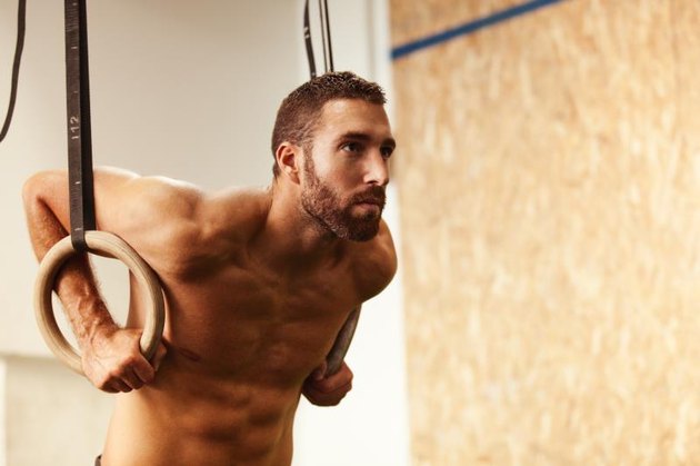 Young fit man is preparing for pulling up on gymnastic rings.