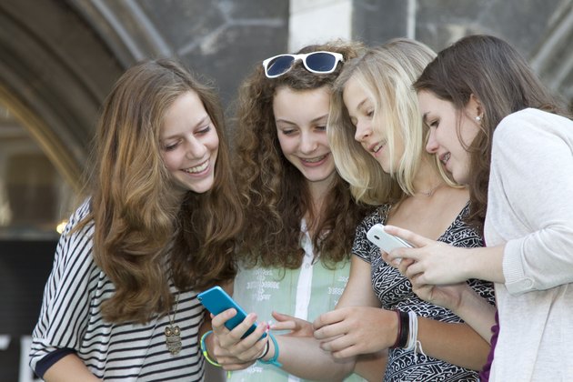 Teenage friends text messaging on cell phones