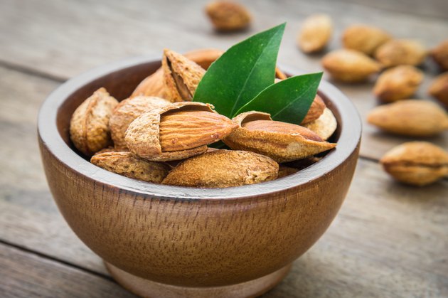 Almond with leaves in wooden bowl