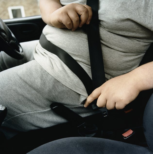 Mid-Section of an Overweight Man Fastening a Car Seatbelt