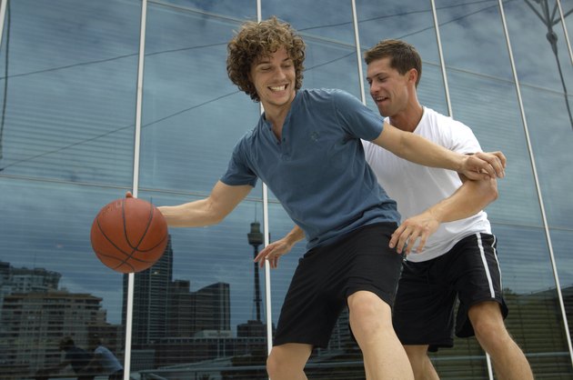 Two young men playing basketball outside office