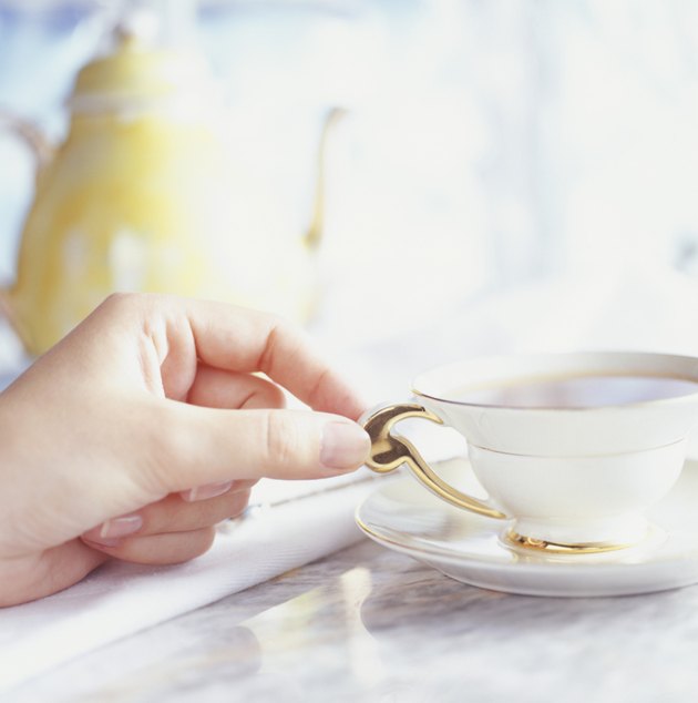 Woman taking tea cup from table, Close-up of hand