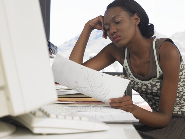 Young woman leaning at desk, looking at document