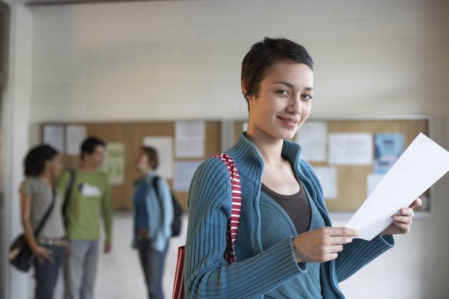 Young woman standing, holding paper, portrait