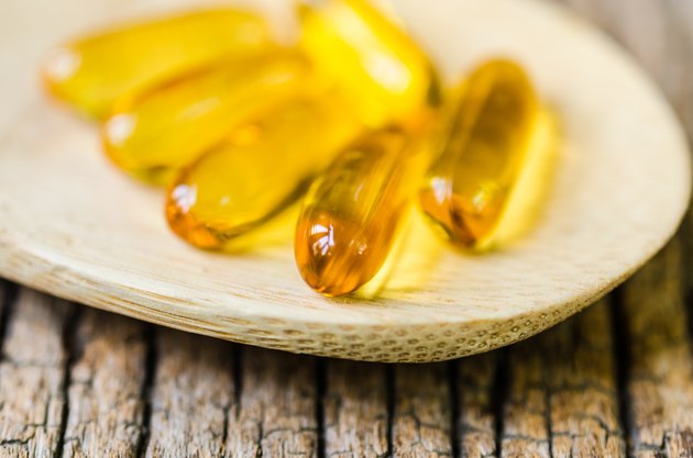 Fish oil on wooden spoon with wooden texture background