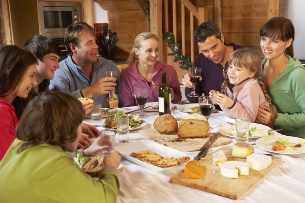 Two Families Enjoying Meal In Alpine Chalet Together