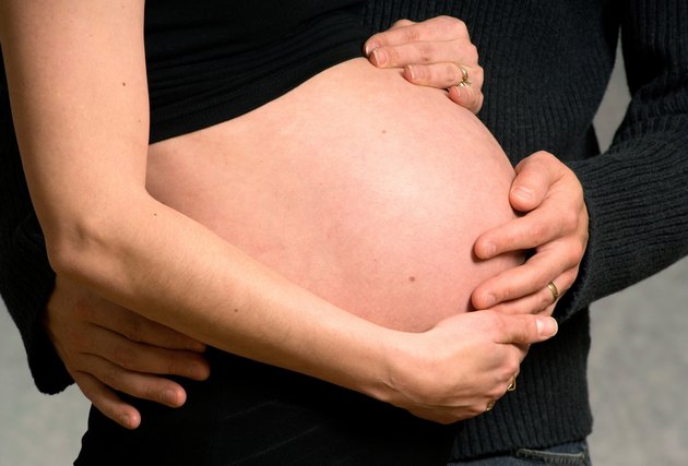 Husband and wife hold mom's belly.