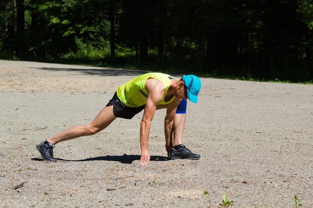 Athlete male runner stretching outdoors. Lizard lunge. Forward lunge elbow to instep.