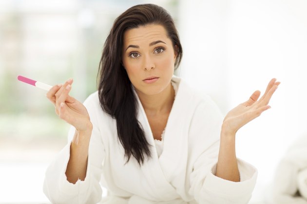 sad young woman holding pregnancy test