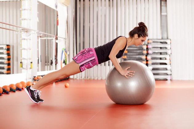 pretty young woman doing pilates exercises with ball