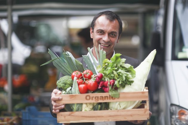 Portrait of mature man holding box of vegetables from market