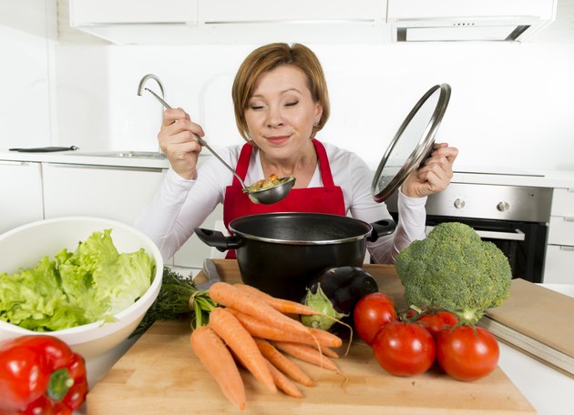 home cook woman at kitchen holding saucepan tasting hot soup