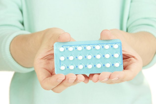 Hormonal pills in female hands isolated on white