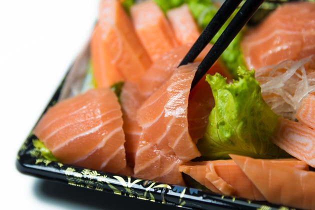 Chopstick grab a slice of Salmon Sashimi Japanese food closeup