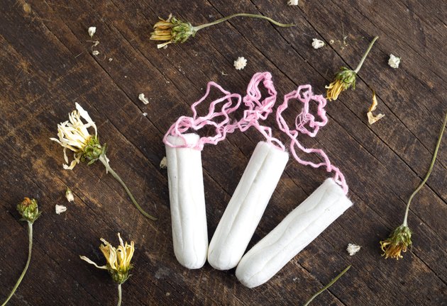 Clean white tampons lying on wooden surface with yellow colored