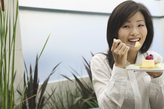 Portrait of a young woman eating from a plate with a fork