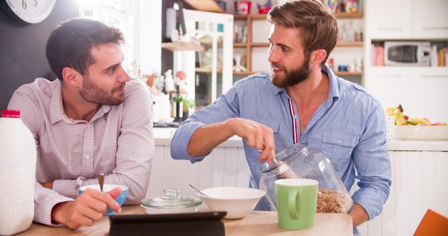 Two Young Men Eating Breakfast In Kitchen Together