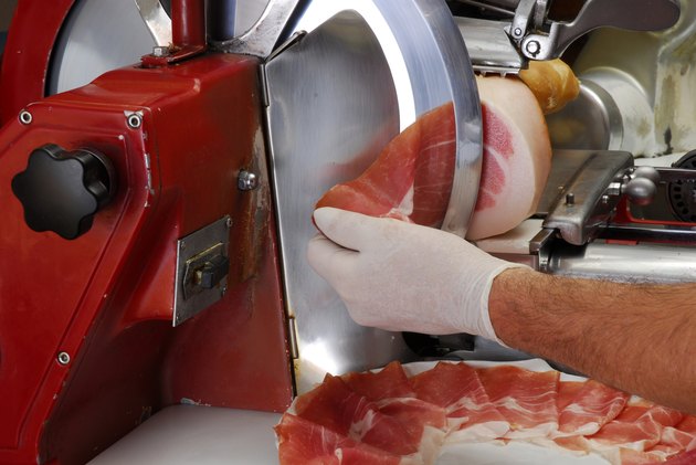 worker slicing ham using machine