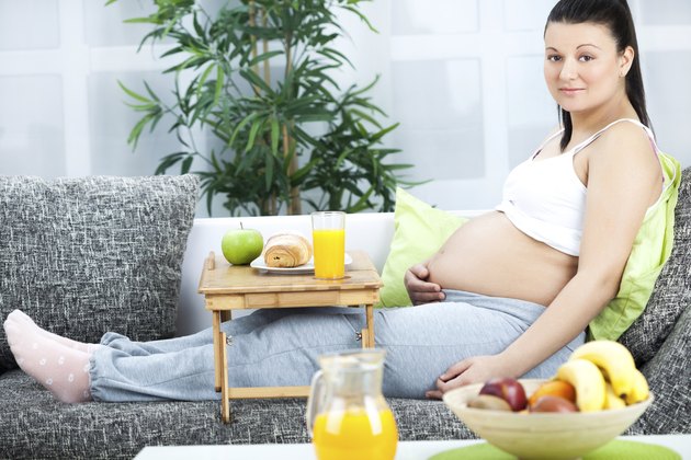 smiling young pregnant woman lying on the sofa