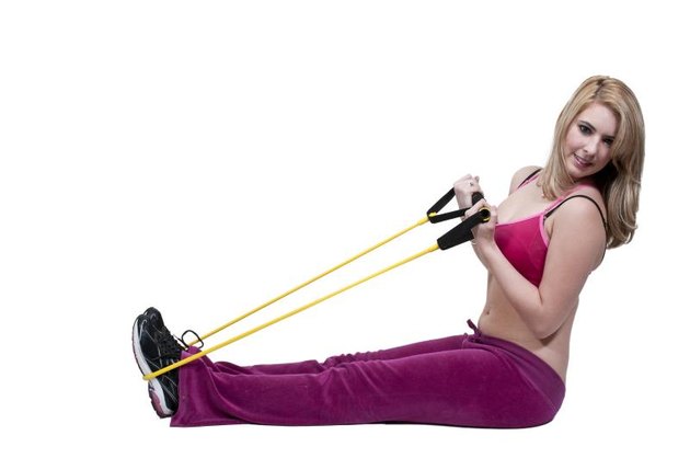 Beautiful young woman working out with resistance band tubes