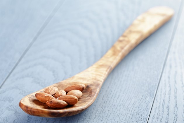 roasted almonds in spoon on blue wooden table