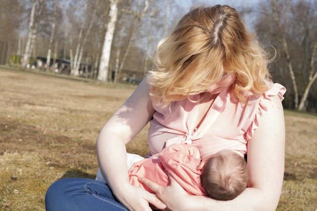 Mother is feeding her baby on the field