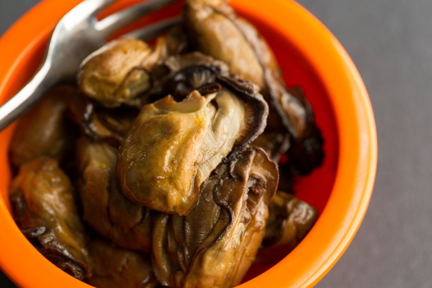 Close view of small whole smoked oysters with fork