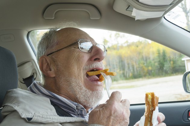 senior man with expressive face eating fast foods