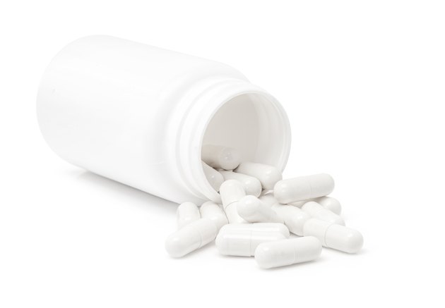 white medicine capsules pouring from bottle isolated on white background