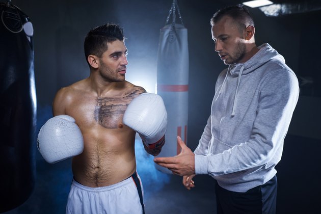 Male coach guiding mid adult boxer