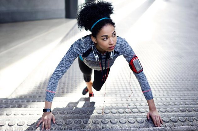 Portrait of fit and sporty young woman doing stretching in city.