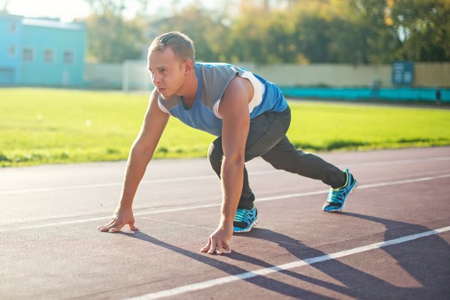 Athletic man standing in posture ready to run on a